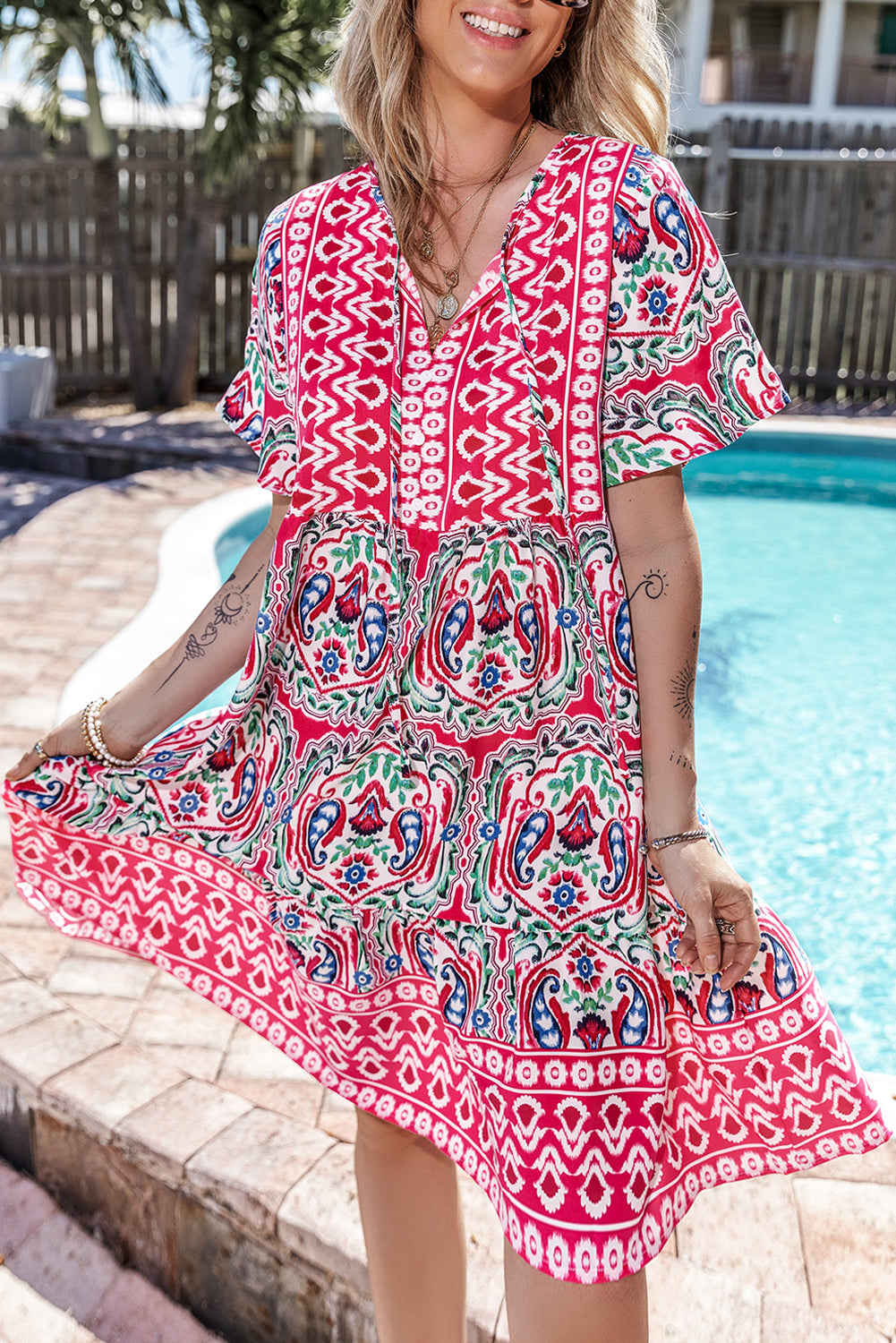 Vestido corto rosa con estampado bohemio, cuello anudado y bajo con volantes