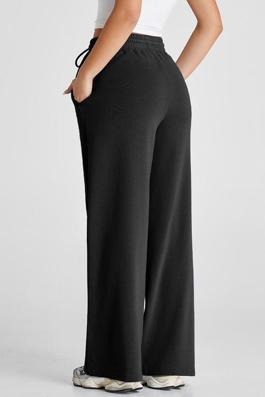 Pantalones deportivos negros de pernera ancha con cordón en la cintura alta y costura vista