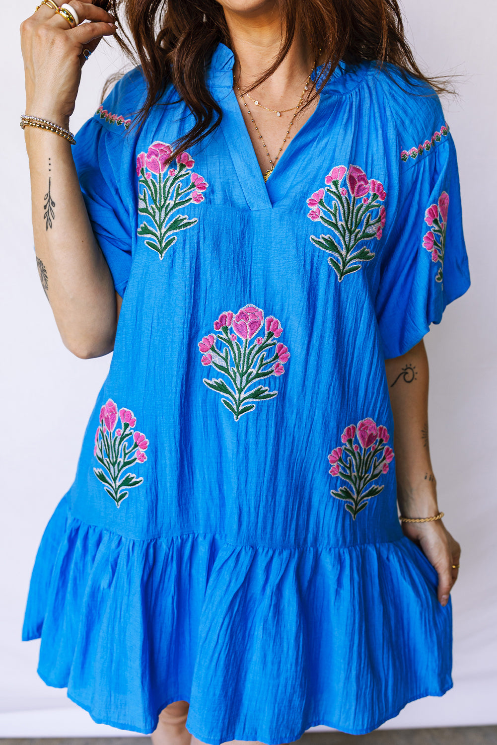 Vestido con bordado de flores azules, cuello dividido, mangas cortas abullonadas y dobladillo con volantes