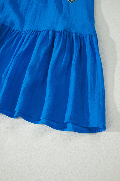 Vestido con bordado de flores azules, cuello dividido, mangas cortas abullonadas y dobladillo con volantes