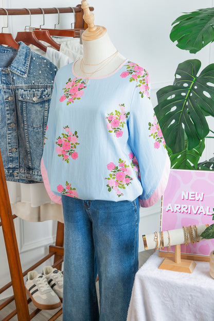 Blusa de manga 3/4 con cuello redondo, botones en los puños y estampado floral azul cielo
