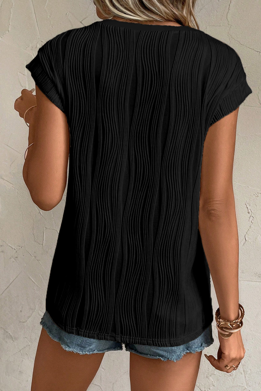 Camiseta negra con textura ondulada y botones en cuello de pico