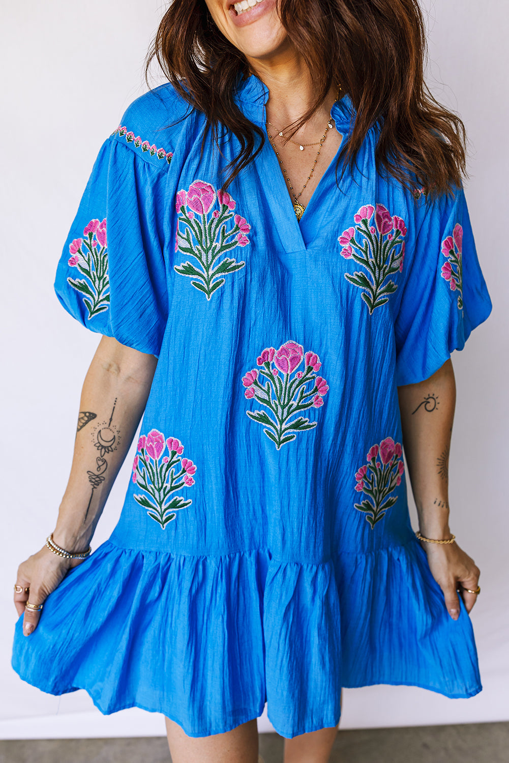 Vestido con bordado de flores azules, cuello dividido, mangas cortas abullonadas y dobladillo con volantes