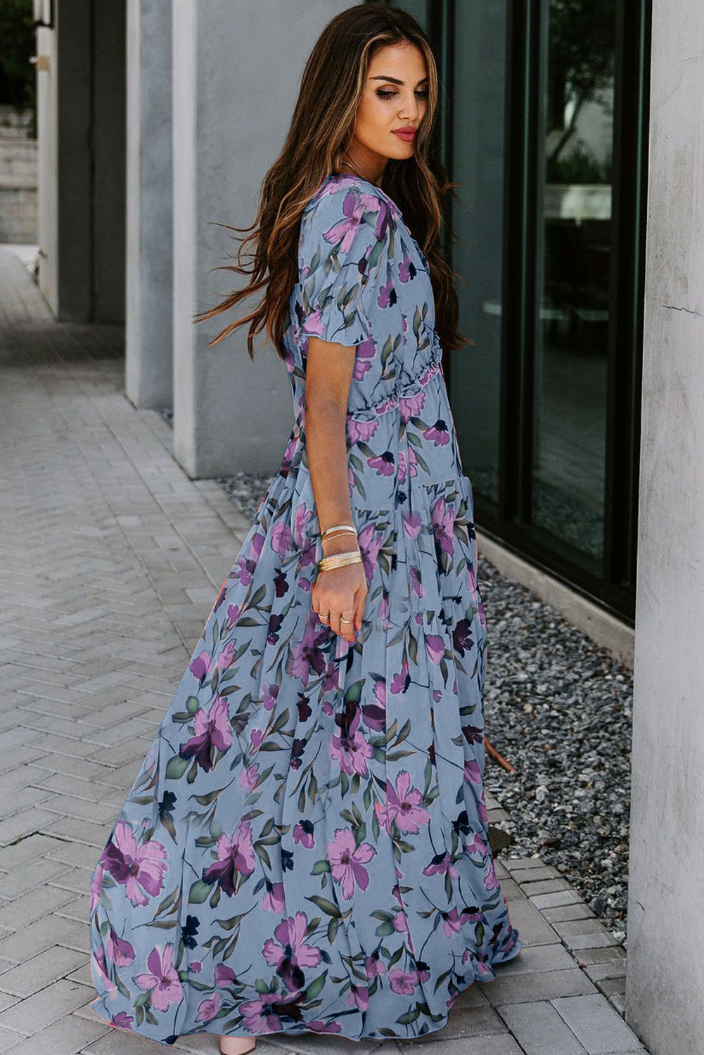 Vestido largo azul cielo con estampado floral intenso, cuello de pico y volantes, y manga corta