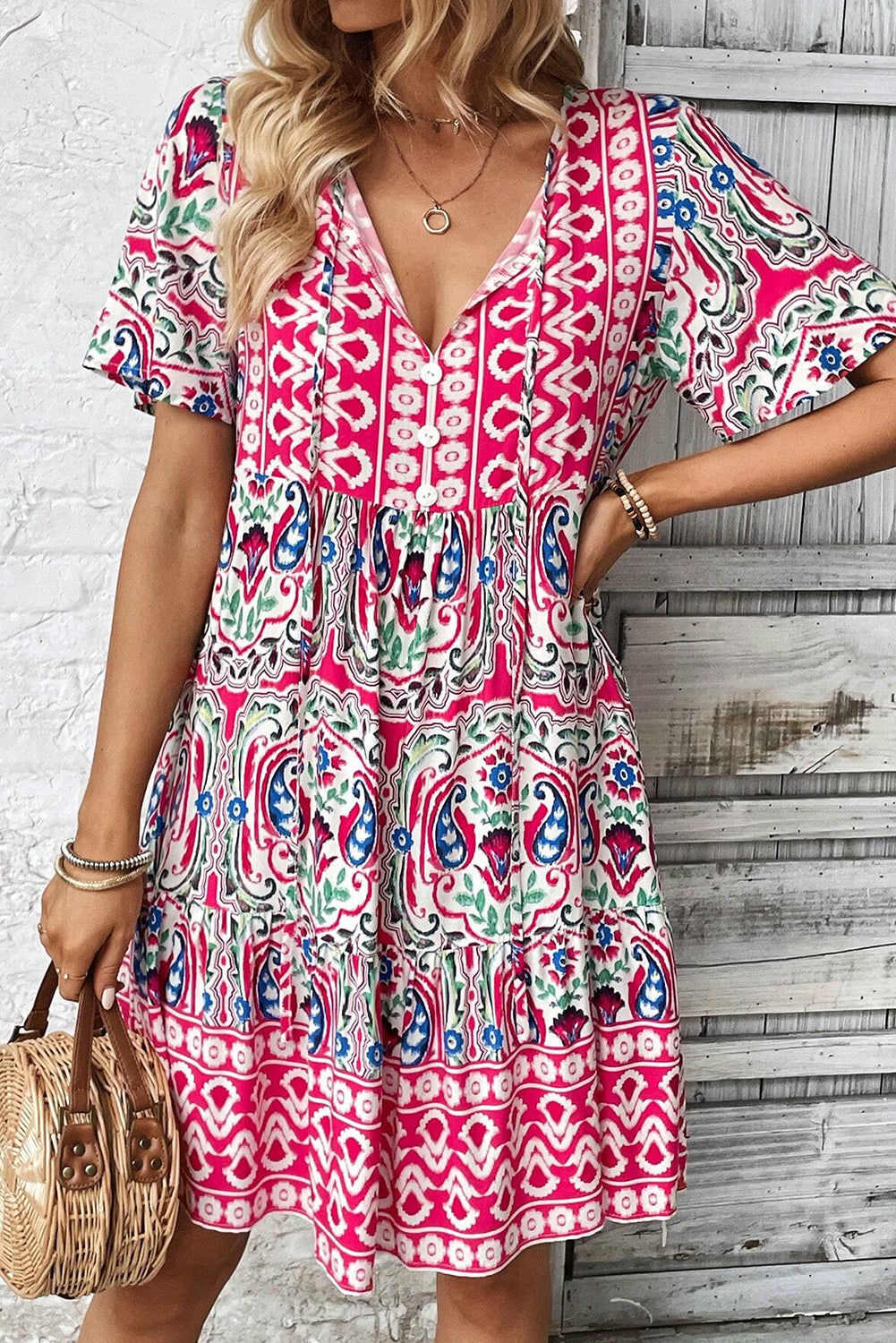 Vestido corto rosa con estampado bohemio, cuello anudado y bajo con volantes