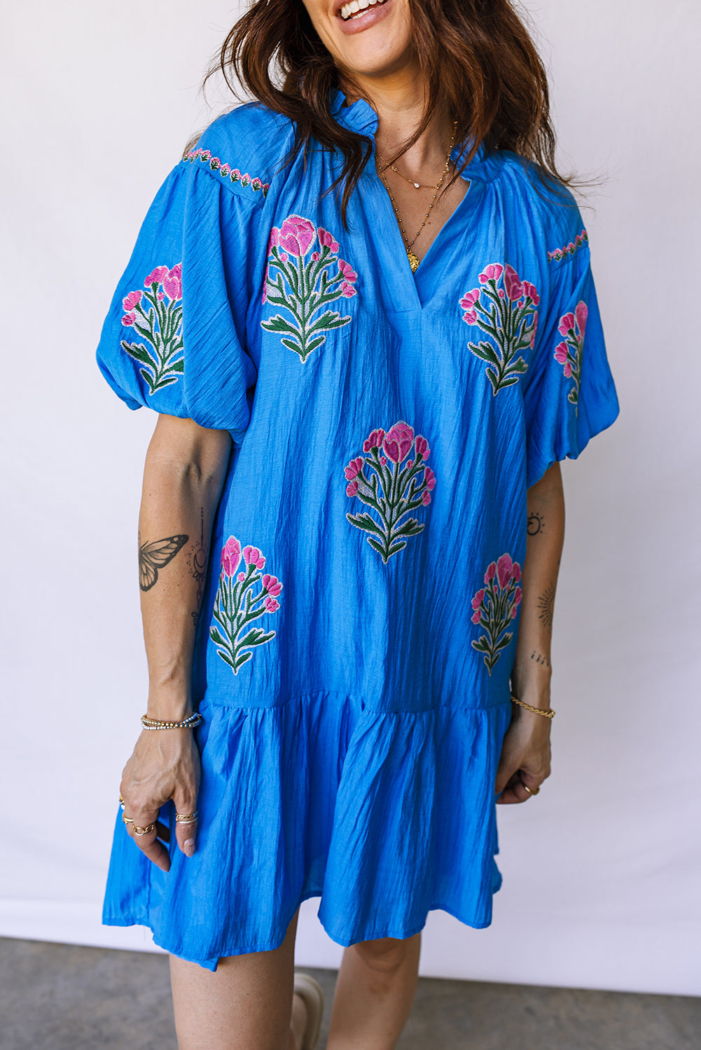 Vestido con bordado de flores azules, cuello dividido, mangas cortas abullonadas y dobladillo con volantes
