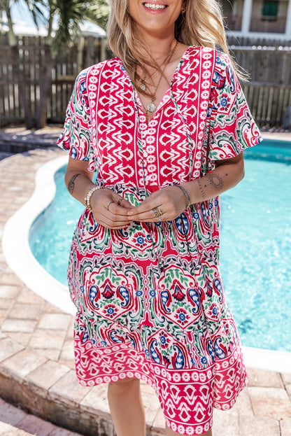Vestido corto rosa con estampado bohemio, cuello anudado y bajo con volantes