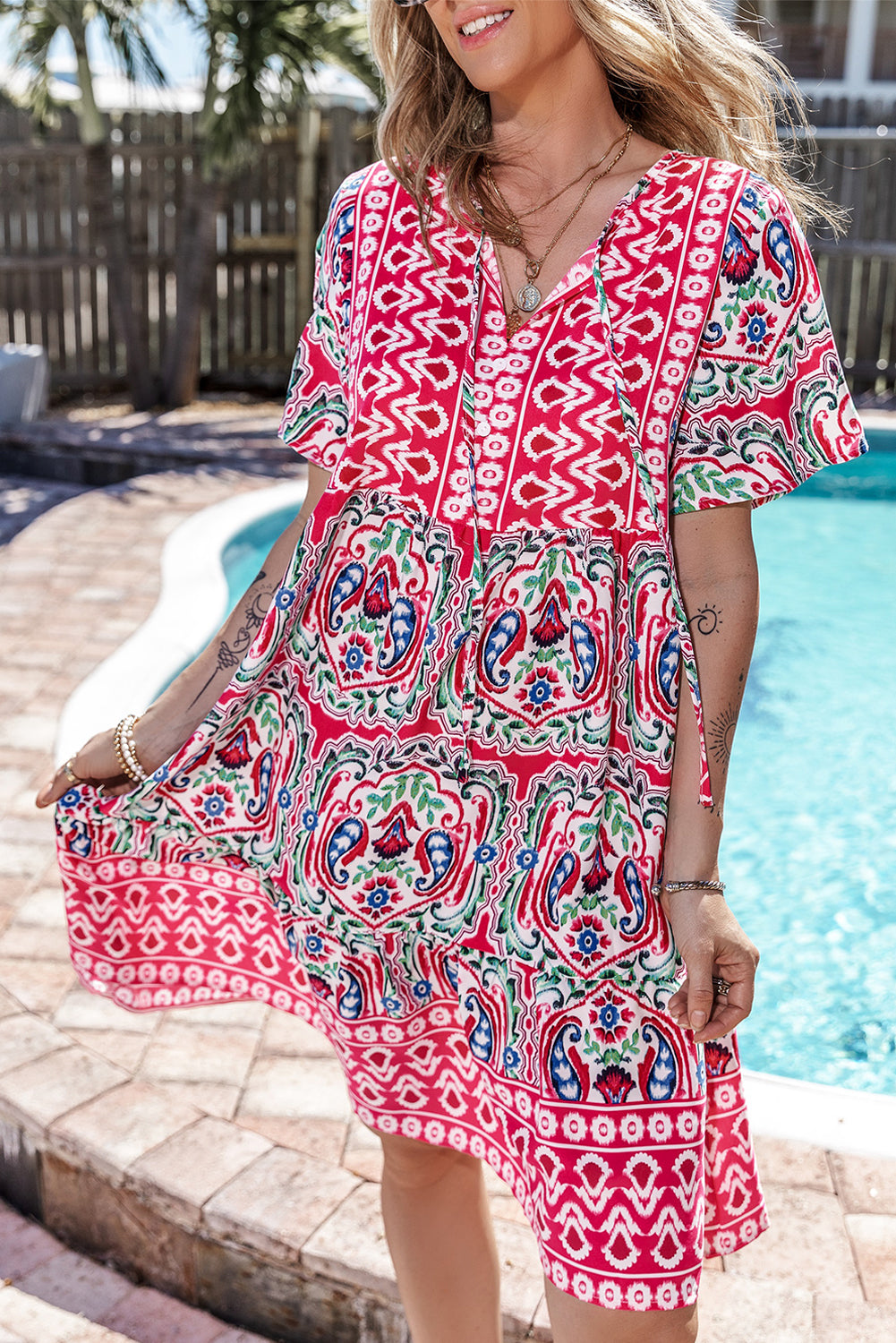 Vestido corto rosa con estampado bohemio, cuello anudado y bajo con volantes