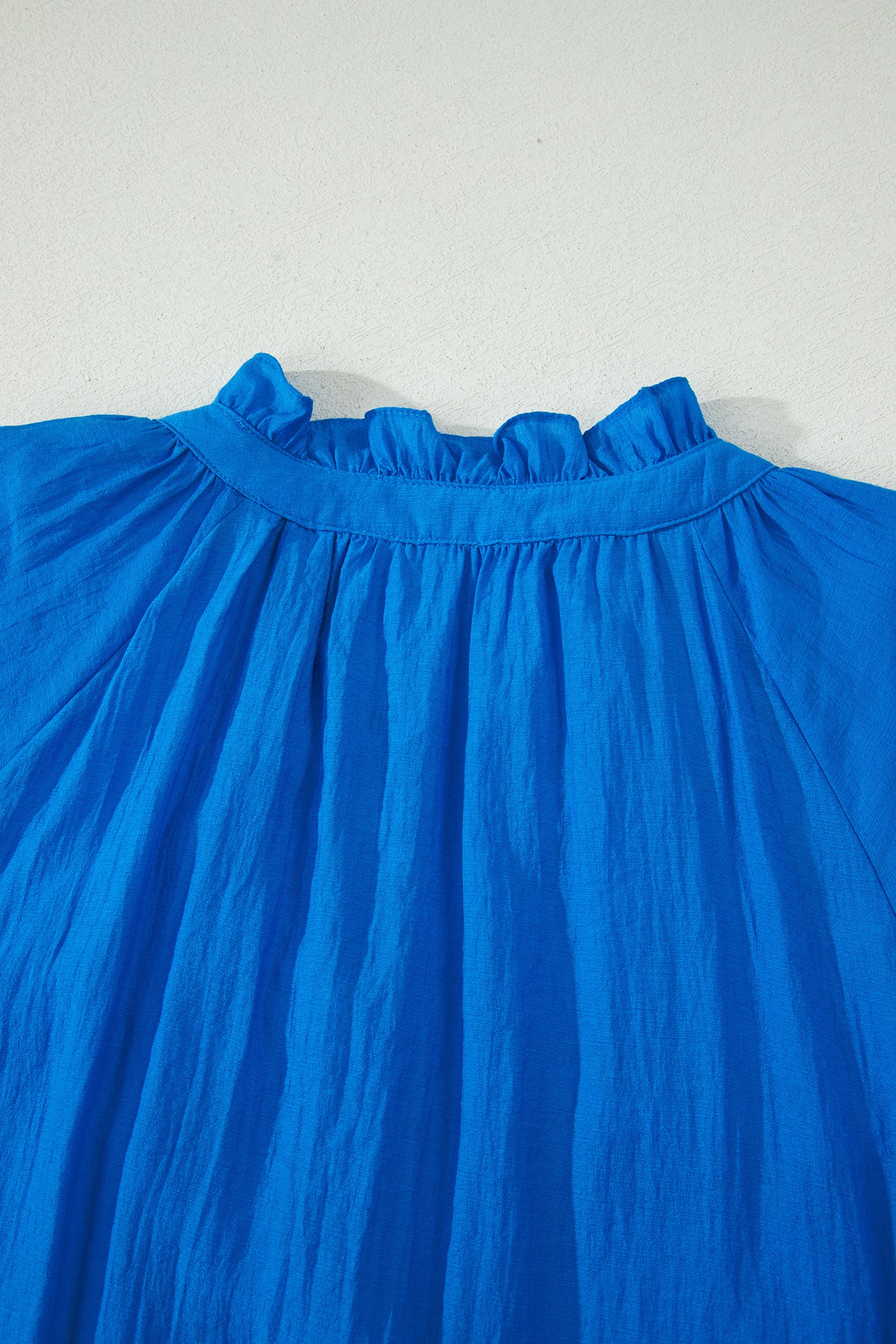 Vestido con bordado de flores azules, cuello dividido, mangas cortas abullonadas y dobladillo con volantes