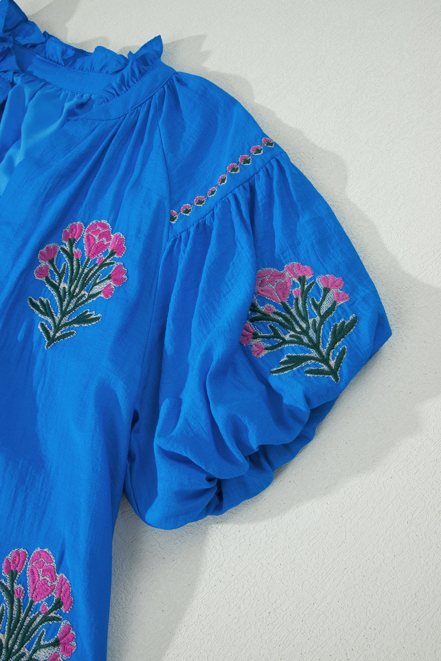 Vestido con bordado de flores azules, cuello dividido, mangas cortas abullonadas y dobladillo con volantes