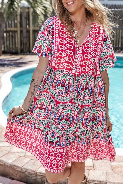 Vestido corto rosa con estampado bohemio, cuello anudado y bajo con volantes